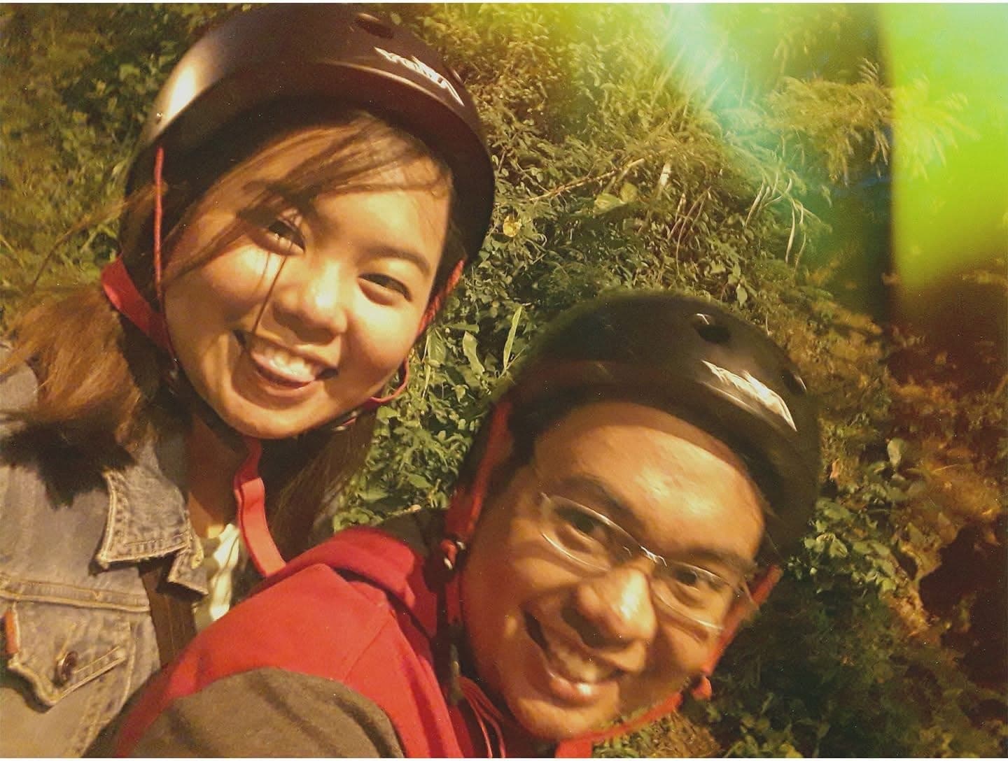 A close-up selfie of Sam and Angela smiling in helmets