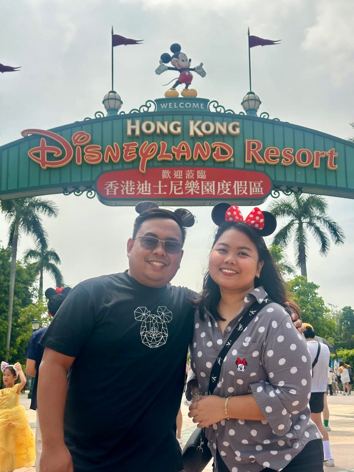 Sam and Angela in Mickey and Minnie ears at the entrance to Hong Kong Disneyland Resort